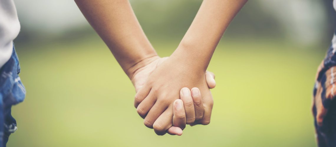 Two little girl friendship hand holding together in the park